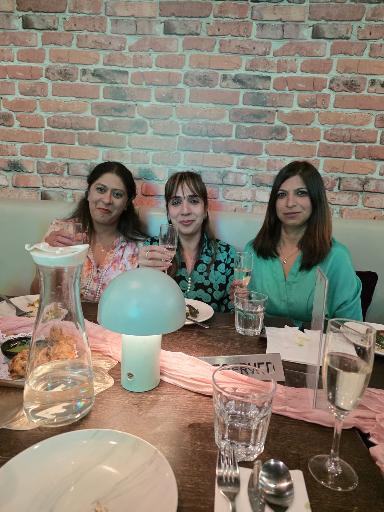 Three guests raising glasses during a celebration at Aura Indian Cuisine